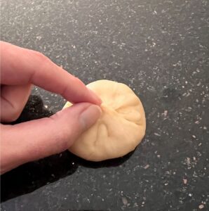 Hand shaping dough by pinching seam together.