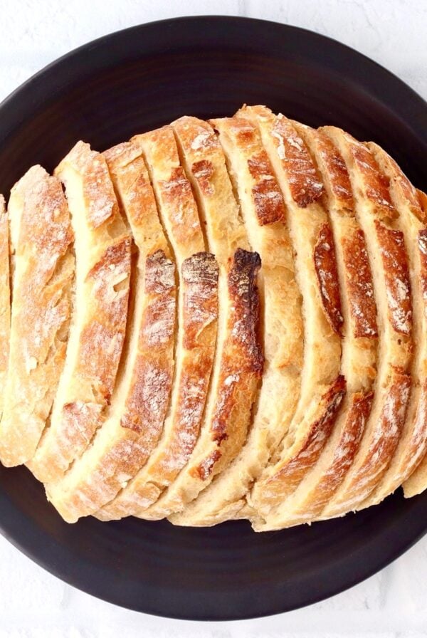 Sliced sourdough bread loaf on black plate.