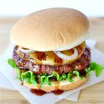 Teriyaki Burger on hamburger bun with lettuce, grilled pineapple ring, and grilled onions.