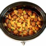 Teriyaki meatballs with pineapple, green onions, and sesame seeds in crock pot.
