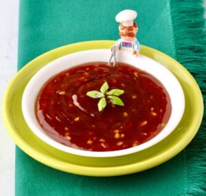 Homemade teriyaki sauce in bowl garnished with green onions, and lego chef with whisk to the side.