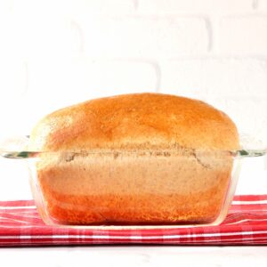 Loaf of homemade whole wheat bread in glass loaf pan.