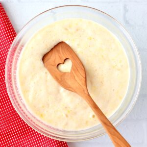 Angel food pineapple dump cake batter in bowl with wooden spoon.