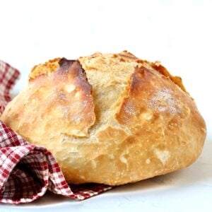 Loaf of homemade artisan bread with dish towel to the side.