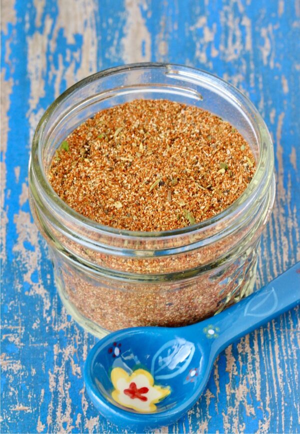 Homemade blackened seasoning mix in small mason jar with blue teaspoon to the side.