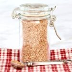 Homemade chili seasoning mix in small jar with teaspoon to the side.