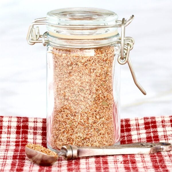 Homemade chili seasoning mix in small jar with teaspoon to the side.