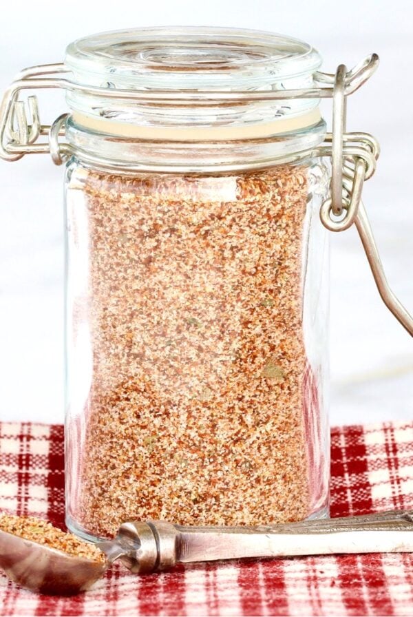 Homemade chili seasoning mix in small jar with teaspoon to the side.