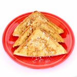 Three slices of cinnamon French toast on plate with powdered sugar sprinkled on top.