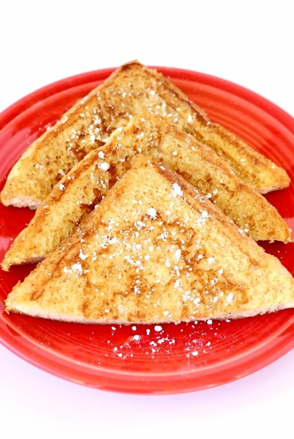 Three slices of cinnamon French toast on plate with powdered sugar sprinkled on top.