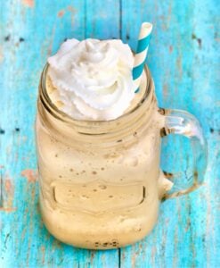 Frozen coffee slush in mason jar mug with whip cream on top.