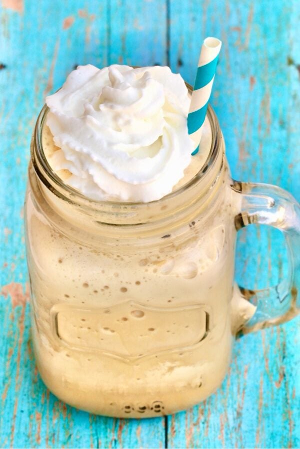 Frozen coffee slush in mason jar mug with whip cream on top.