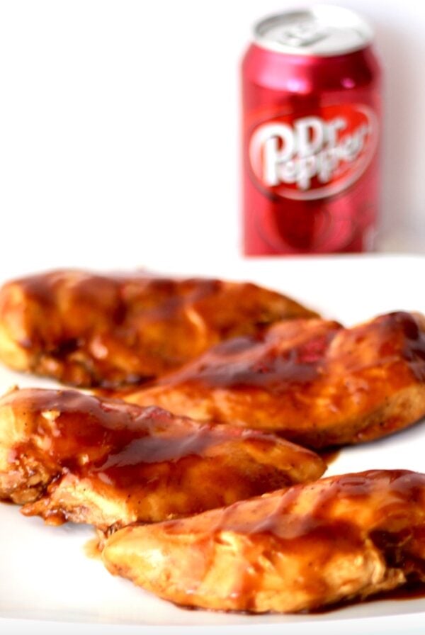 Four pieces of Dr Pepper BBQ Sauce chicken on plate with can of Dr. Pepper in background.