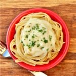 Alfredo Sauce on fettuccine noodles in small bowl with fork to the side.
