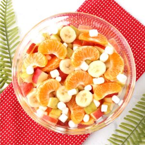 Fruit salad with oranges, apples, pears, bananas and mini marshmallows in bowl.