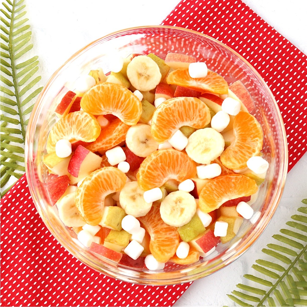 Fruit salad with oranges, apples, pears, bananas and mini marshmallows in bowl.
