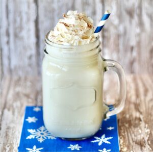 Hot vanilla milk in mason jar mug topped with whipped cream and cinnamon.