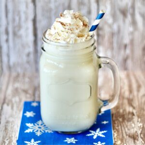 Hot vanilla milk in mason jar mug topped with whipped cream and cinnamon.