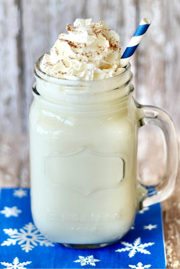 Hot vanilla milk in mason jar mug topped with whipped cream and cinnamon.