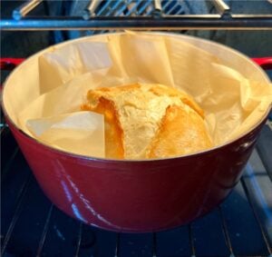Artisan bread baking in oven, inside dutch oven.