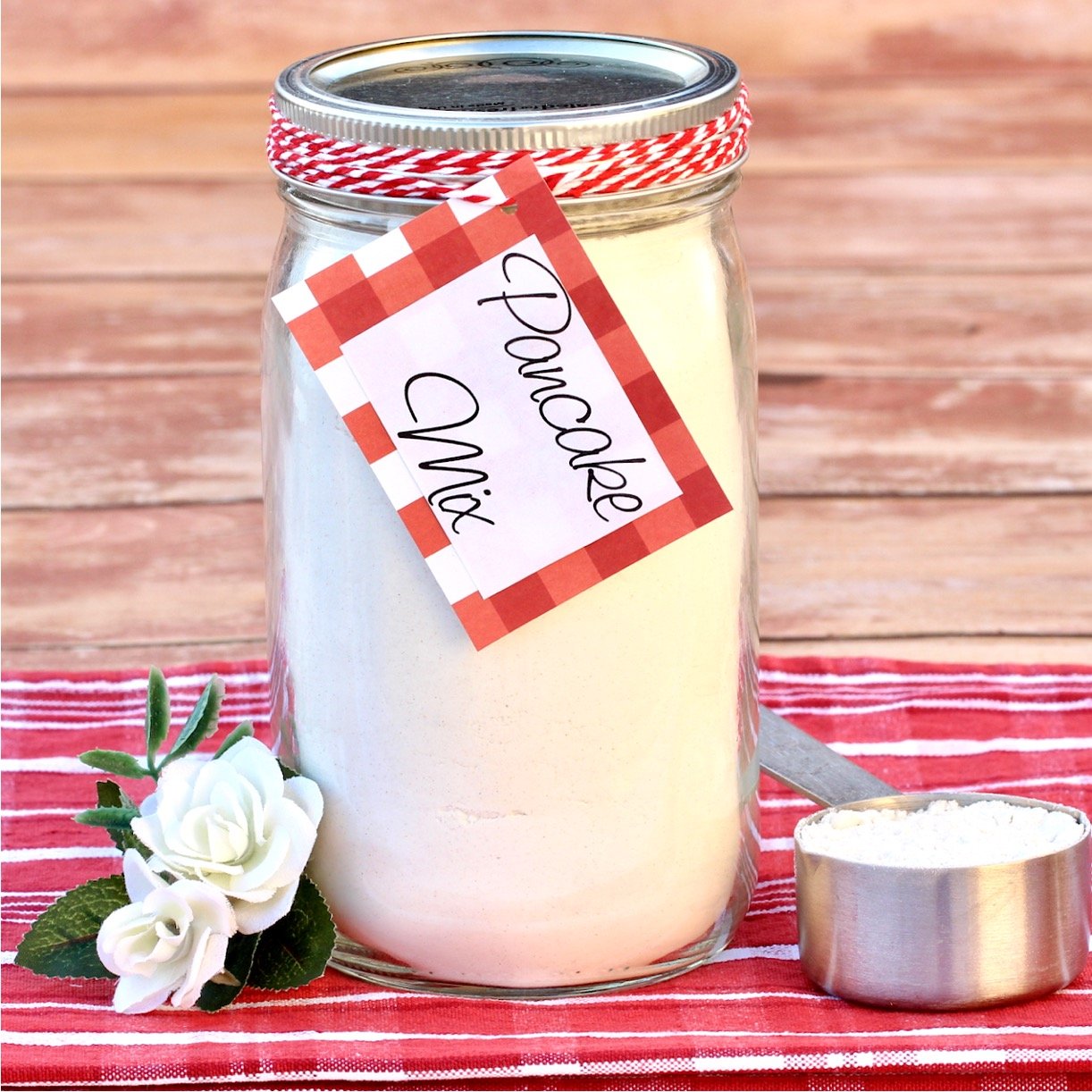 Homemade pancake mix in mason jar with measuring cup to the side.