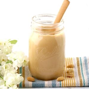 Creamy homemade peanut butter in mason jar with spoon.