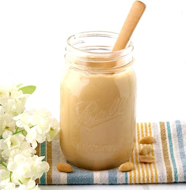 Creamy homemade peanut butter in mason jar with spoon.