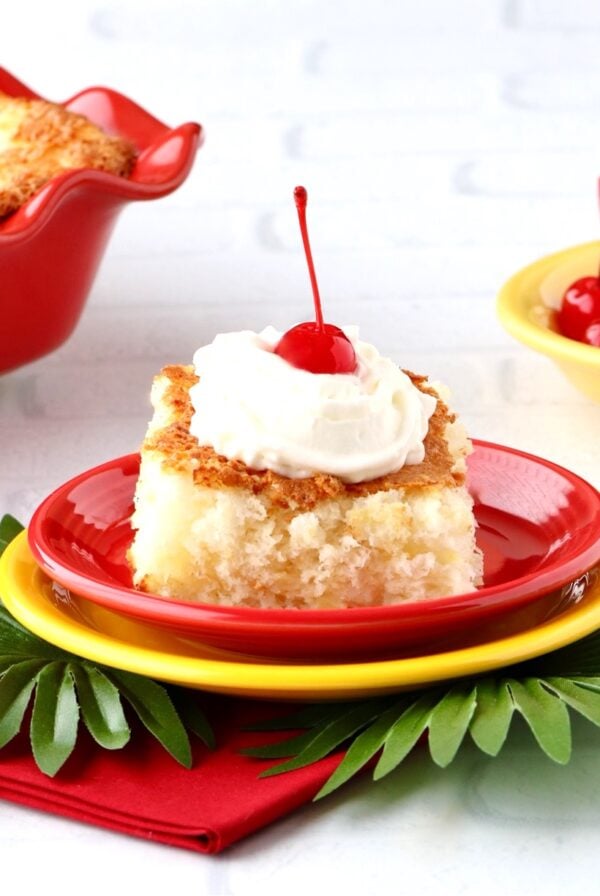 Slice of pineapple angel food cake with whip cream and a cherry on top.