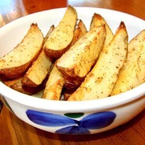 Baked seasoned potato wedges in bowl.
