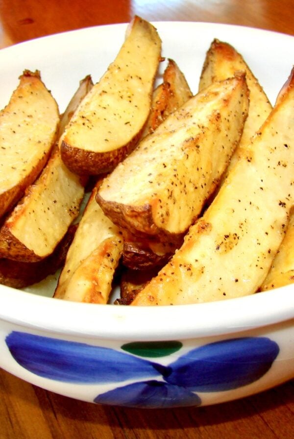 Baked seasoned potato wedges in bowl.