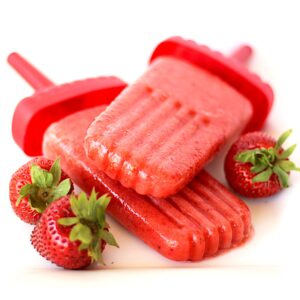 Two strawberry popsicles with fresh strawberries to the side.