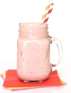 Strawberry protein shake in mason jar mug with two straws.