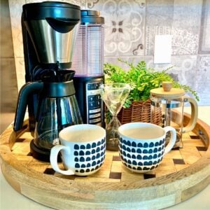 Coffee maker, French press, and 2 mugs on kitchen counter coffee bar tray.