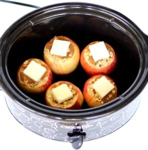 Five apples with cinnamon, butter, and oats ready to be baked in crockpot.