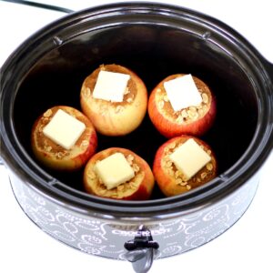 Five apples with cinnamon, butter, and oats ready to be baked in crockpot.