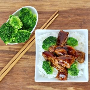 Beef and broccoli on plate with rice, and chopsticks to the side.