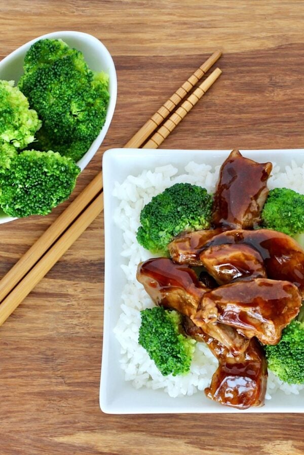 Beef and broccoli on plate with rice, and chopsticks to the side.