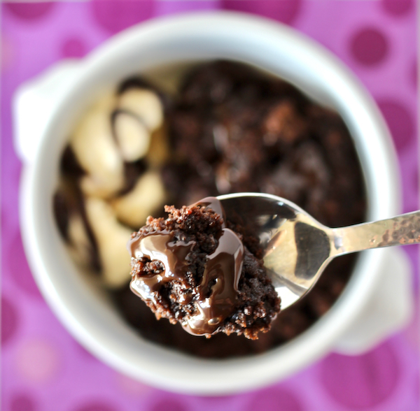 Chocolate lava cake bite on spoon with bowl in background.