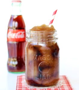 Frozen coke in mason jar with Coca-Cola bottle in the background.