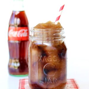 Frozen coke in mason jar with Coca-Cola bottle in the background.