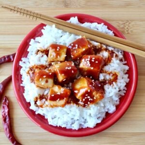 General Tso Chicken on plate with rice and chopsticks.