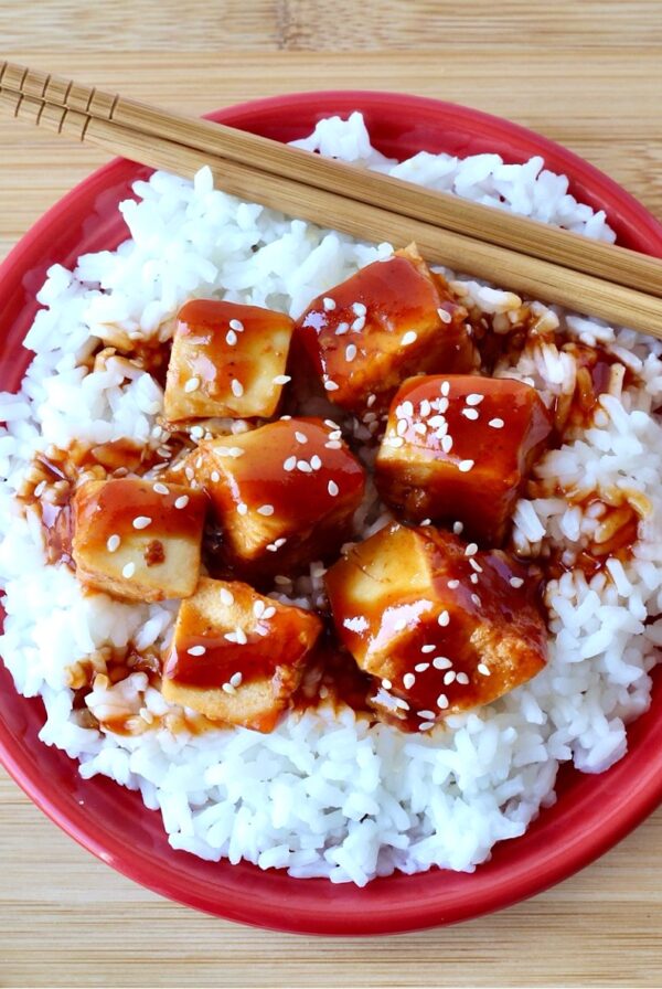 General Tso Chicken on plate with rice and chopsticks.