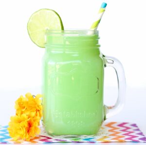 Green punch in mason jar with lime slice and straws.