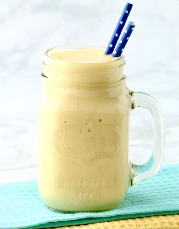 Mango smoothie in mason jar mug.