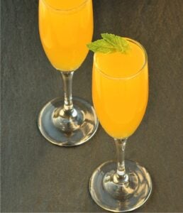 Peach Bellini mocktail in two glasses, garnished with mint leaves.