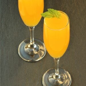 Peach Bellini mocktail in two glasses, garnished with mint leaves.