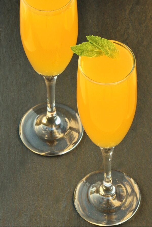Peach Bellini mocktail in two glasses, garnished with mint leaves.