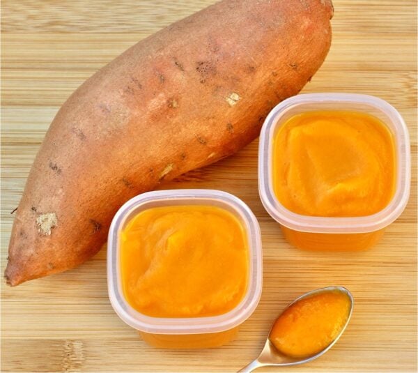 Sweet potato baby food in two containers, with sweet potato to the side.