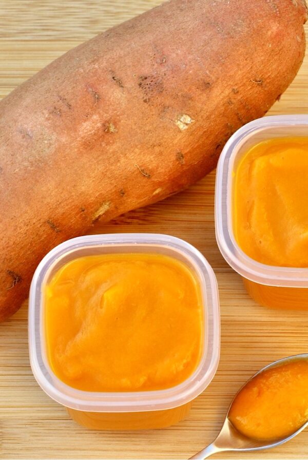 Sweet potato baby food in two containers, with sweet potato to the side.