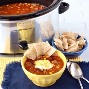 Taco soup in bowl with chips, and crock pot in background.